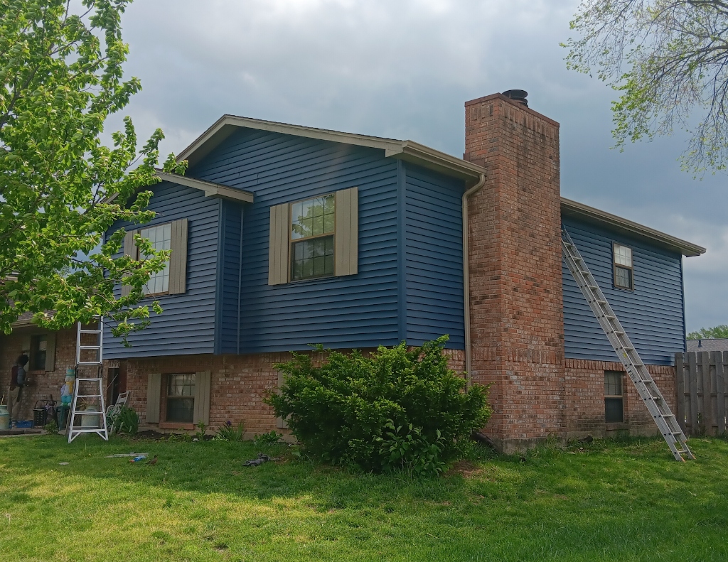 Blue siding installation with ladder